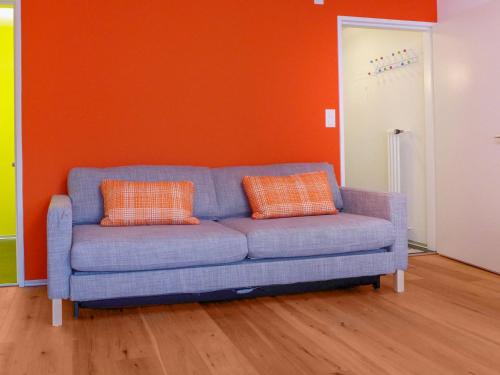 ツェルマットにあるApartment Viscaria-2 by Interhomeのオレンジ色の壁の客室で、青いソファが備わります。