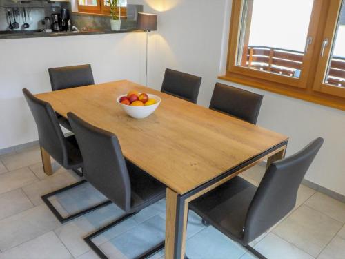 uma mesa de madeira com cadeiras e uma taça de fruta em Apartment Breithorn by Interhome em Zermatt