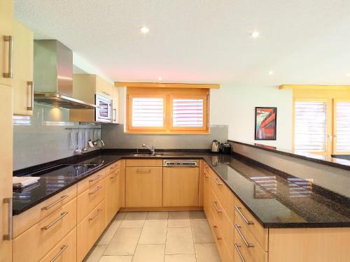 a large kitchen with wooden cabinets and black counter tops at Apartment Breithorn by Interhome in Zermatt