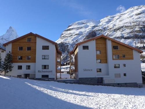 zwei Gebäude vor einem schneebedeckten Berg in der Unterkunft Apartment Silence-1 by Interhome in Zermatt