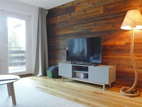 ツェルマットにあるApartment Residence A-2 by Interhomeの木製の壁にテレビ付きのリビングルーム