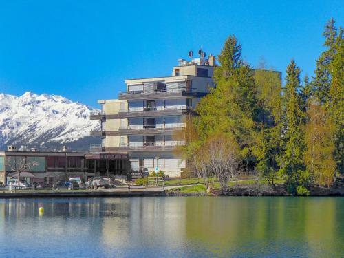 a building next to a lake with a mountain at Apartment Jeanne d'Arc-1 by Interhome in Crans-Montana