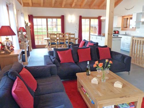 sala de estar con sofá azul y almohadas rojas en Chalet Helene by Interhome, en Ovronnaz