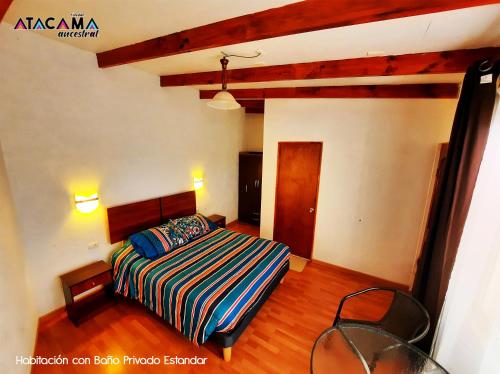 1 dormitorio con 1 cama con una manta a rayas de colores en Hostal Atacama Ancestral, en San Pedro de Atacama