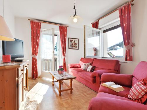 sala de estar con sofás rojos y TV en Apartment Ghetta by Interhome, en Vigo di Fassa