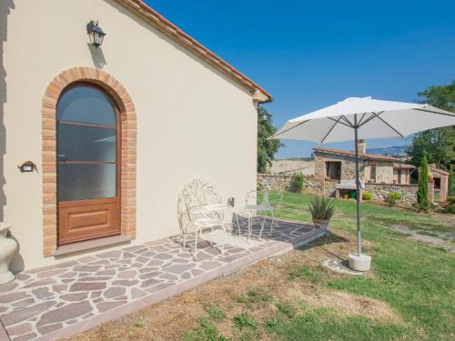 un patio con sombrilla, 2 sillas y una puerta en Apartment Podere Sant'Elisa-3 by Interhome, en Pomarance