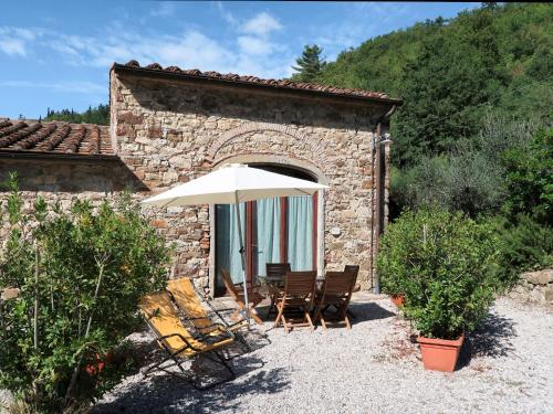 eine Terrasse mit Stühlen und einem Sonnenschirm vor einem Gebäude in der Unterkunft Holiday Home Castiglioni-1 by Interhome in Castiglione