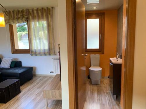 a bathroom with a toilet and a living room at Casas Natura in Graus