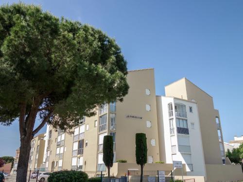 un bâtiment avec un arbre devant lui dans l'établissement Studio Les Sables d'Or-10 by Interhome, au Grau-du-Roi