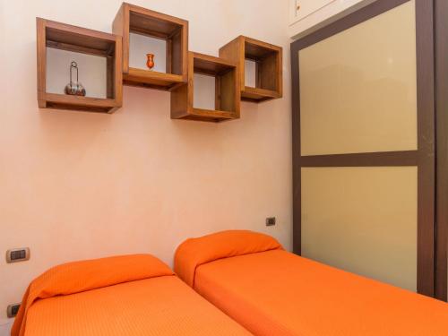 a bedroom with an orange bed and wooden shelves at Apartment Appartamento Doria - REI186 by Interhome in Monte Nai