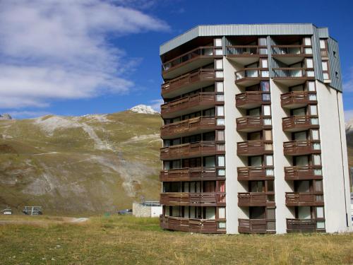 un grand immeuble dans un champ avec une montagne dans l'établissement Apartment Le Borsat - Val Claret-4 by Interhome, à Tignes