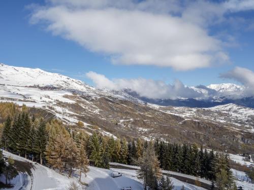 a snow covered mountain with trees and snow capped mountains at Studio Vostok Zodiaque-34 by Interhome in Le Corbier