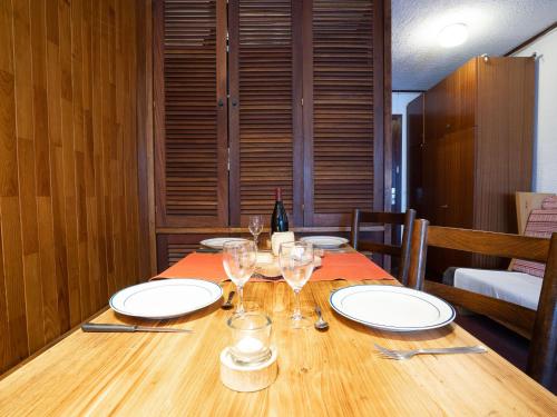a wooden table with plates and wine glasses on it at Apartment Le Grand Tichot A et B - Val Claret-3 by Interhome in Tignes