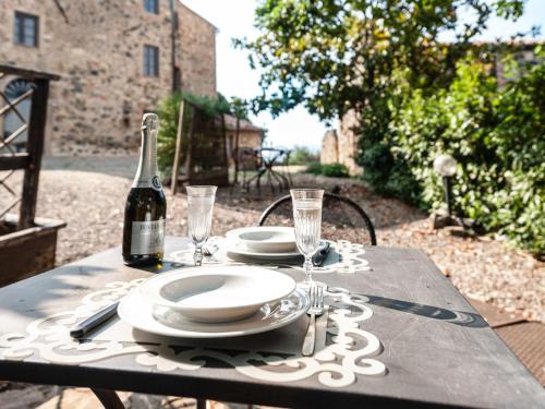 a table with plates and glasses and a bottle of wine at Apartment Borgo Cerbaiola-1 by Interhome in Casa Montacuto