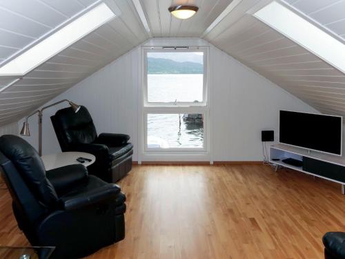 uma sala de estar com 2 cadeiras e uma televisão de ecrã plano em Holiday Home Rorbu - FJS555 by Interhome em Naustdal i Sunnfjord