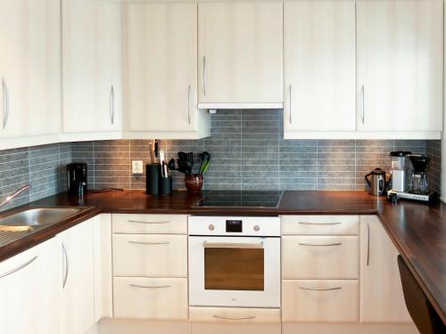 uma cozinha com armários brancos e um forno com placa de fogão em Holiday Home Rorbu - FJS555 by Interhome em Naustdal i Sunnfjord