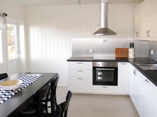Una cocina con gabinetes blancos y una mesa con sillas. en Holiday Home Solsvika by Interhome, en Leirvik