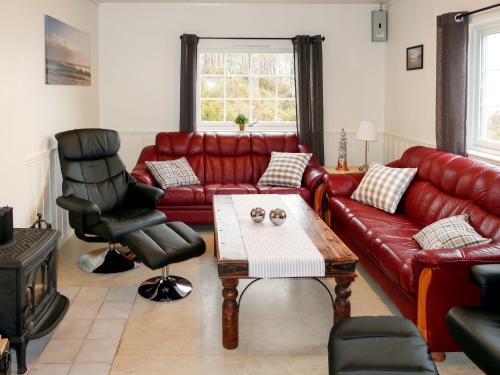 Una sala de estar con un sofá de cuero rojo y una mesa. en Holiday Home Solsvika by Interhome, en Leirvik