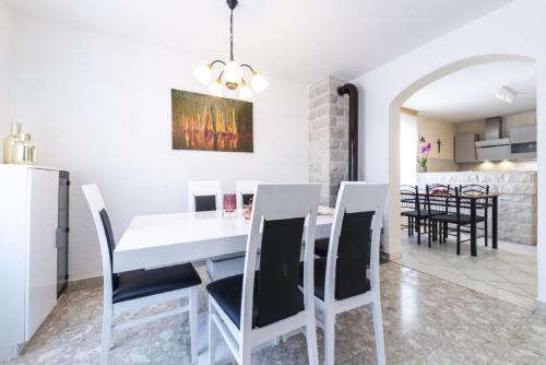 a kitchen and dining room with a white table and chairs at Holiday Home Swiss in Cavtat