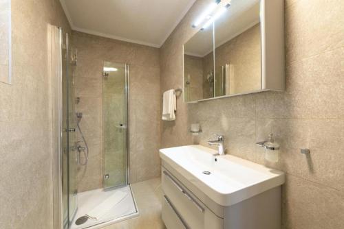 a bathroom with a sink and a shower and a mirror at Holiday Home Swiss in Cavtat