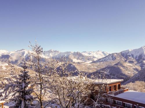 una casa en la nieve con montañas en el fondo en Apartment Pegase Phenix-55, en Le Corbier