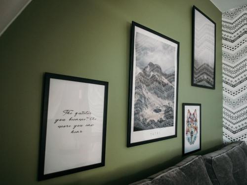 a green wall with four framed pictures on it at Willa Pachówka - tam, gdzie natura spotyka się z nowoczesnością in Bukowina Tatrzańska