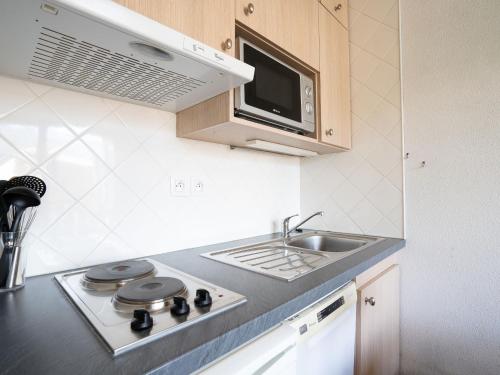 een keuken met een wastafel, een fornuis en een magnetron bij Apartment L'Argousier-1 by Interhome in Les Menuires