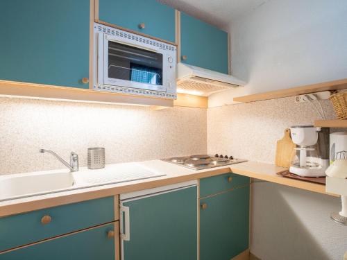 a small kitchen with blue cabinets and a microwave at Apartment Le Jettay-13 by Interhome in Les Menuires