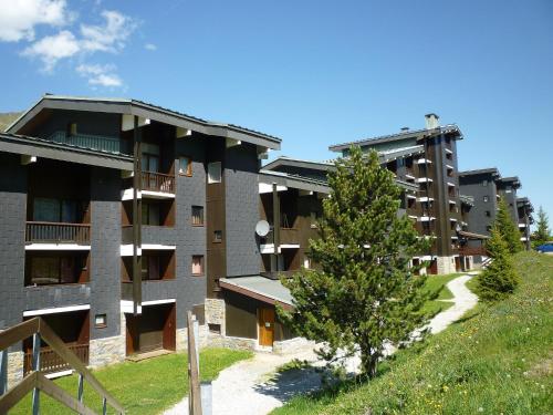 ein Apartmenthaus mit einem Baum davor in der Unterkunft Apartment Le Jettay-15 by Interhome in Les Menuires