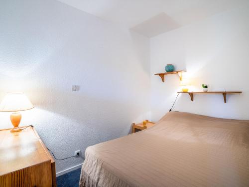 une chambre avec un lit, une table et une lampe dans l'établissement Apartment Vostok Zodiaque-52 by Interhome, au Corbier