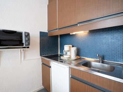 Apartment Belleville Caron-7 by Interhome في ليه مينوير: مطبخ صغير مع حوض وميكروويف
