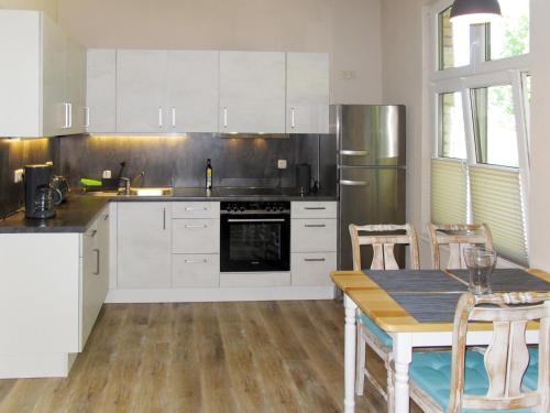una cocina con electrodomésticos blancos y una mesa con sillas. en Apartment Helene by Interhome, en Ribnitz-Damgarten