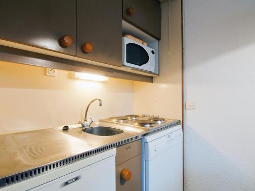 a small kitchen with a sink and a microwave at Apartment Le Villaret-2 by Interhome in Les Menuires