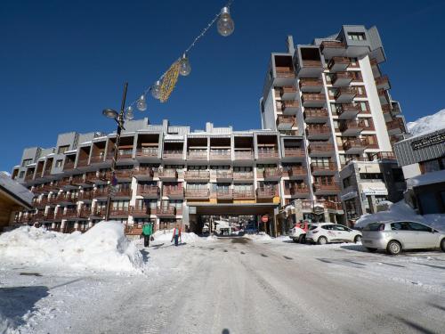 a large building on a snowy street with cars parked in front at Apartment Le Curling B-21 by Interhome in Tignes