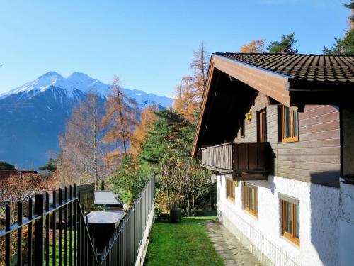 a house with a fence and mountains in the background at Holiday Home Waldruh by Interhome in Telfs
