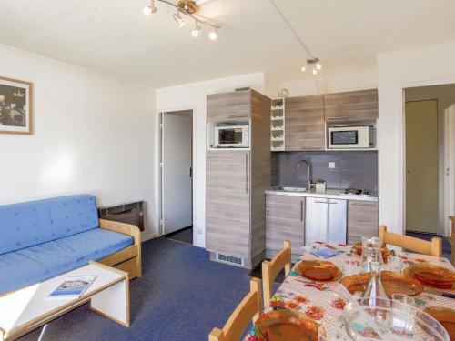un salon avec un canapé bleu et une cuisine dans l'établissement Apartment Vostok Zodiaque-56 by Interhome, au Corbier