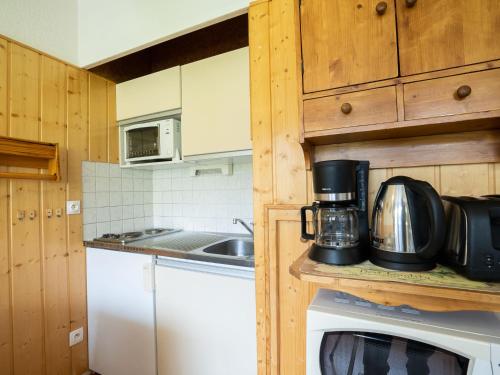 een keuken met houten kasten en een magnetron bij Apartment Asters 98 Bâtiment C3 by Interhome in Les Menuires