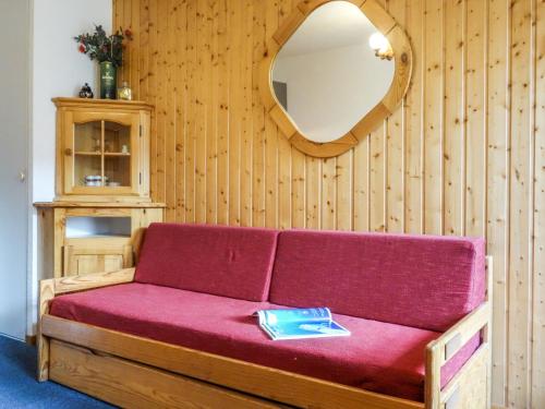 a red couch with a mirror on a wooden wall at Apartment La Divaria-6 in Tignes