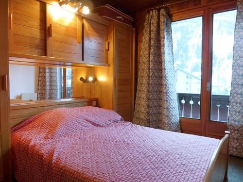 a bedroom with a bed with a red comforter and a window at Apartment Les Charmoz-3 by Interhome in Chamonix