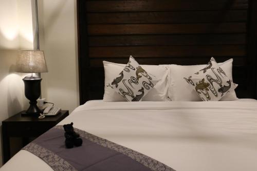 a bed with a black cat sitting on top of it at Kampaeng Ngam Hotel in Chiang Mai