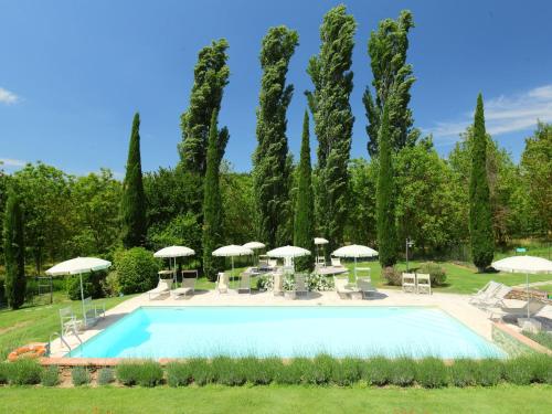 a pool with tables and umbrellas in a garden at Apartment Aia by Interhome in Rapolano Terme