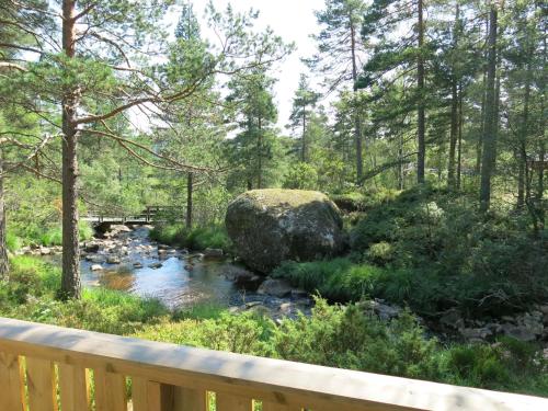 a stream in the woods with a wooden bridge at Holiday Home Berthabu - SOW116 by Interhome in Øyuvstad
