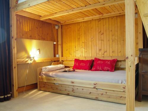 Cette chambre en bois comprend un lit avec des oreillers rouges. dans l'établissement Apartment Les Aiguilles du Brévent by Interhome, à Chamonix-Mont-Blanc