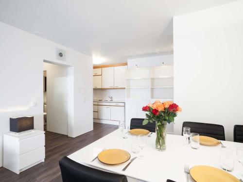 Apartment Wildhorn 222 by Interhome في ليه كولون: غرفة طعام مع طاولة بيضاء مع زهور في مزهرية