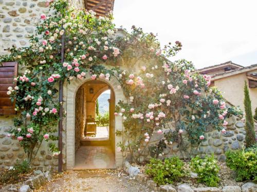 an archway with pink roses on a stone building at Apartment Allerona-3 by Interhome in Allerona
