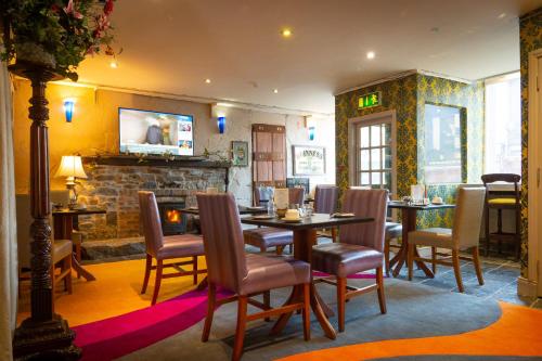 a dining room with tables and chairs and a fireplace at Ashley Hotel in Cork