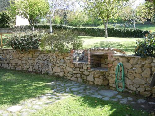 a stone wall in a yard with a green hose at Holiday Home Casa Graziani-5 by Interhome in Ravigliano