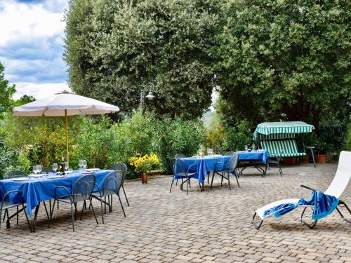 a patio with blue tables and chairs and an umbrella at Holiday Home Casa Graziani-5 by Interhome in Ravigliano