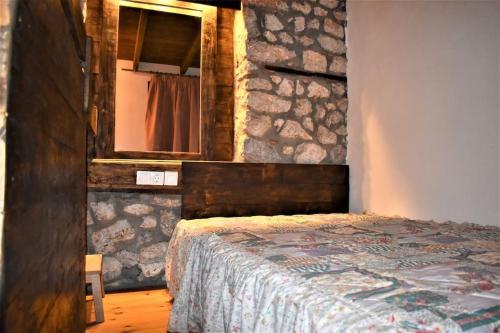 1 dormitorio con 1 cama en una pared de piedra en Μικρή Πέτρινη Μεζονέτα 2, en Lílaia