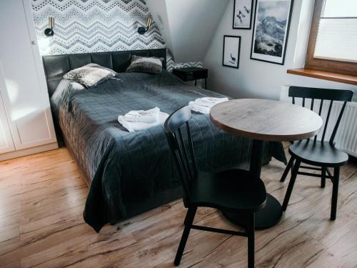 a bedroom with a bed and a table and chairs at Willa Pachówka - tam, gdzie natura spotyka się z nowoczesnością in Bukowina Tatrzańska